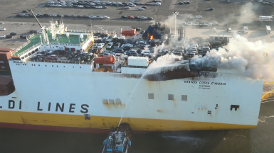 A fire boat directing water onto the Grande Costa D’Avorio at a port