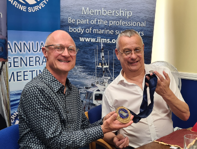 Mike Proudlove (left) accepting the President's medal from IIMS CEO, Mike Schwarz, at the 2026 AGM